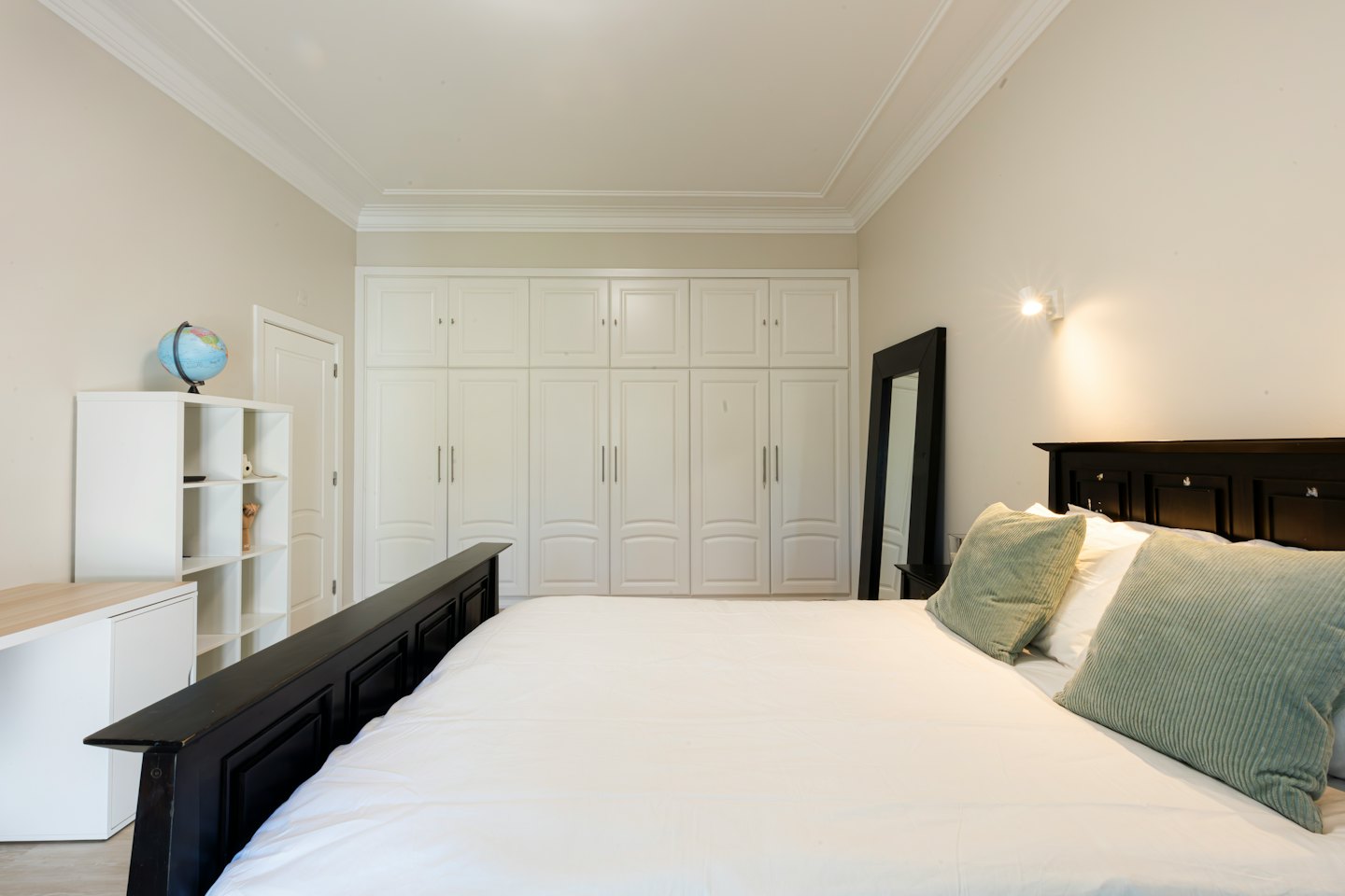 Modern bedroom with a white bed and built-in wardrobes.
